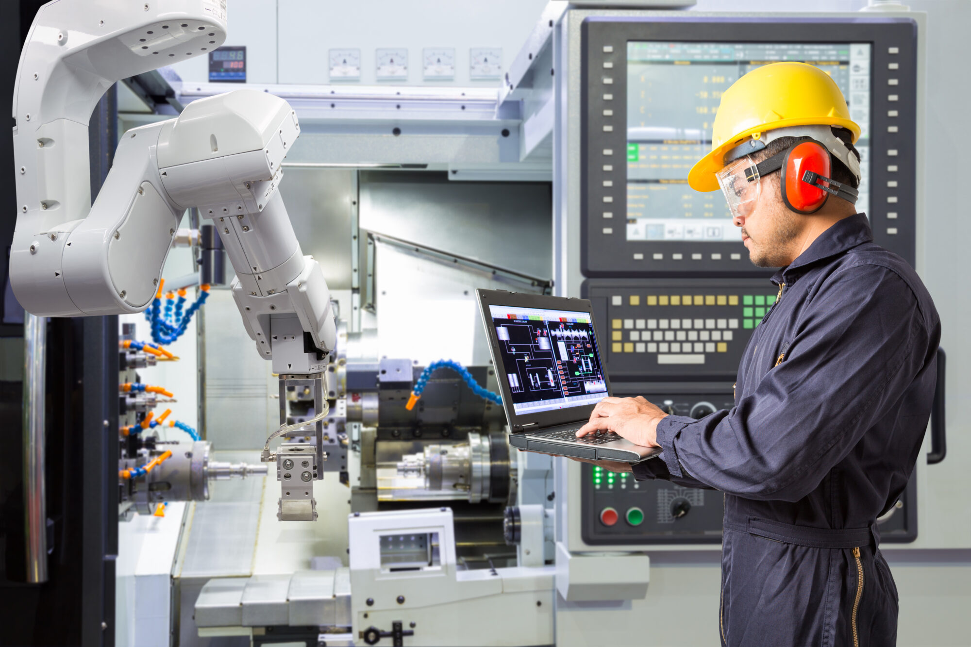 Maintenance engineer using laptop computer control automatic robotic hand on a CNC machine